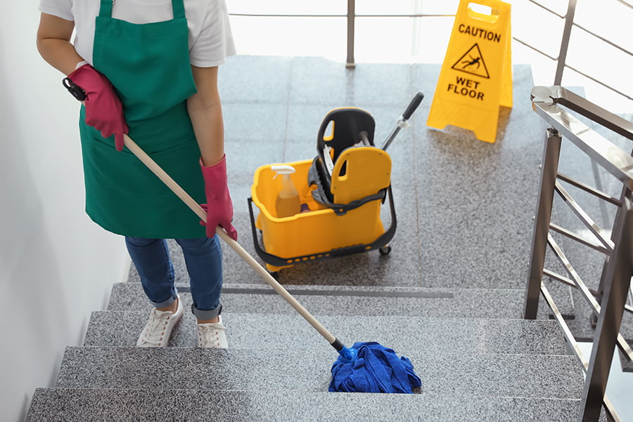 Young woman with mop cleaning stairs